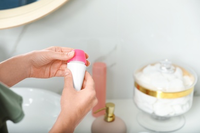Photo of Woman holding deodorant in bathroom, closeup view