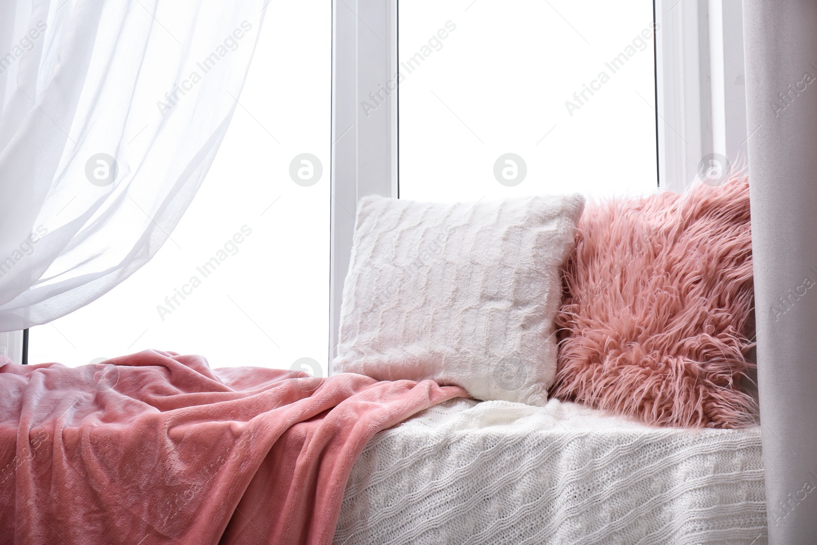 Photo of Soft pillows and plaids on window sill in room. Cozy place to relax