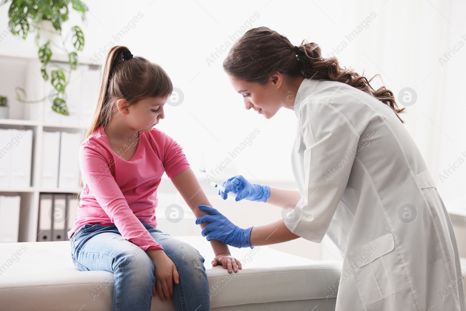 Photo of Little girl receiving chickenpox vaccination in clinic. Varicella virus prevention