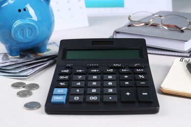 Calculator, piggy bank, money, glasses and notebooks on white table. Pension planning