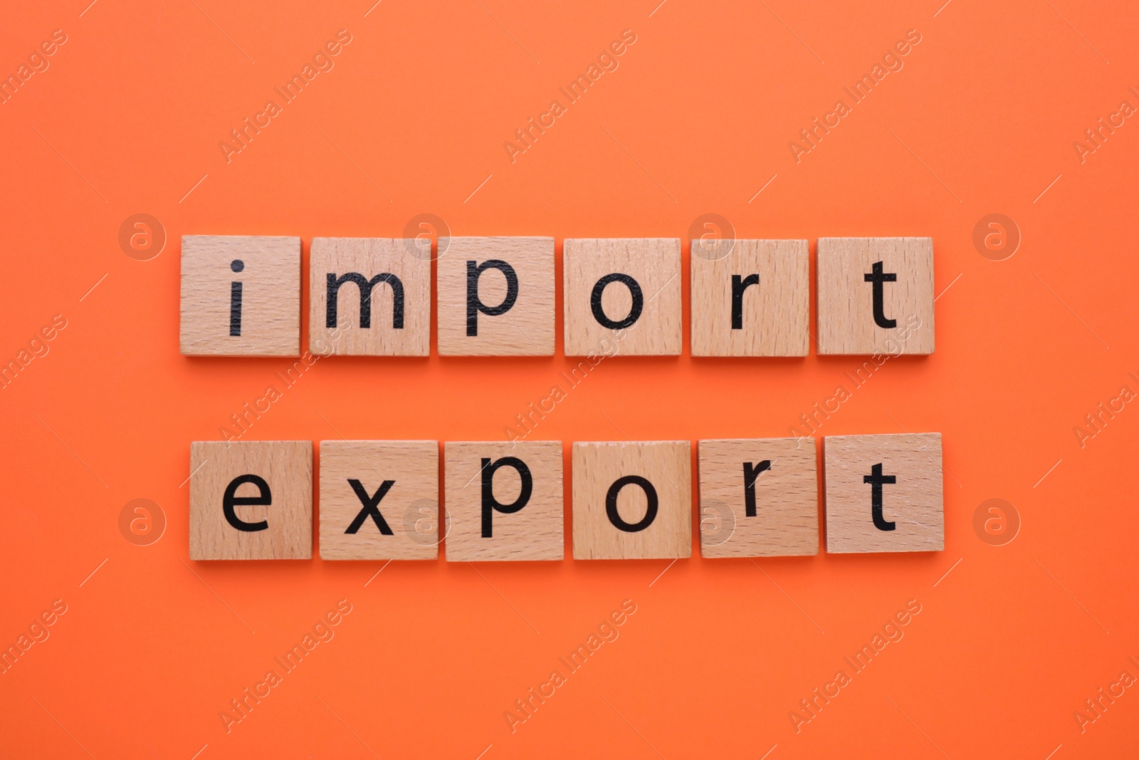 Photo of Words Import and Export made of wooden squares on orange background, top view