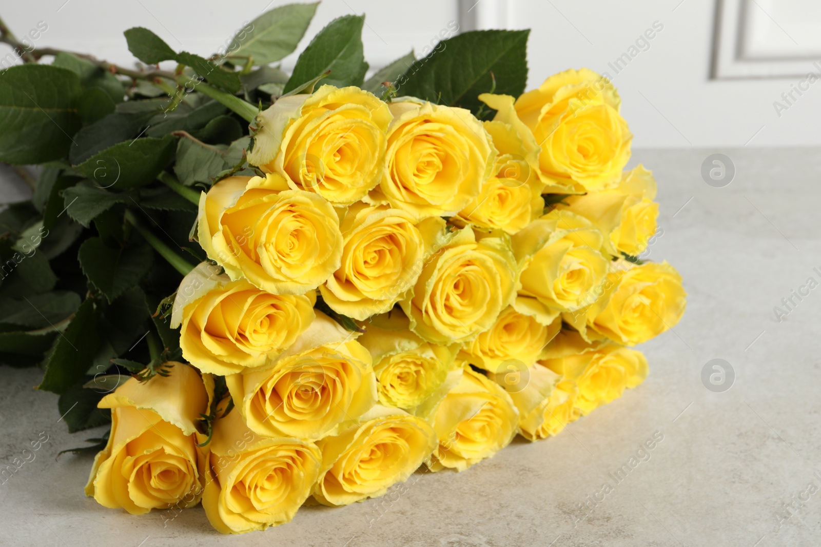 Photo of Beautiful bouquet of yellow roses on light grey table