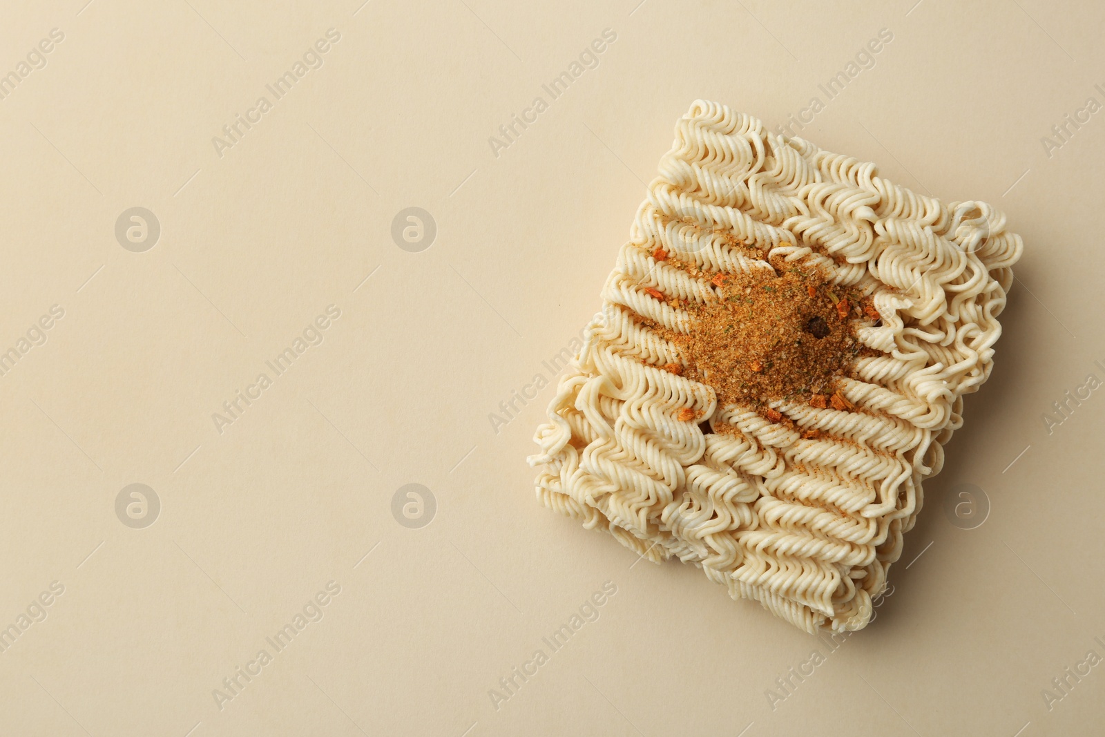 Photo of Block of quick cooking noodles with spices on color background, top view. Space for text