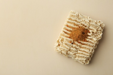 Block of quick cooking noodles with spices on color background, top view. Space for text