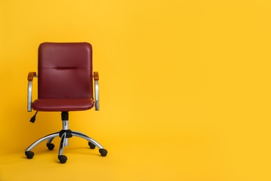 Photo of Modern office chair on yellow background. Space for text