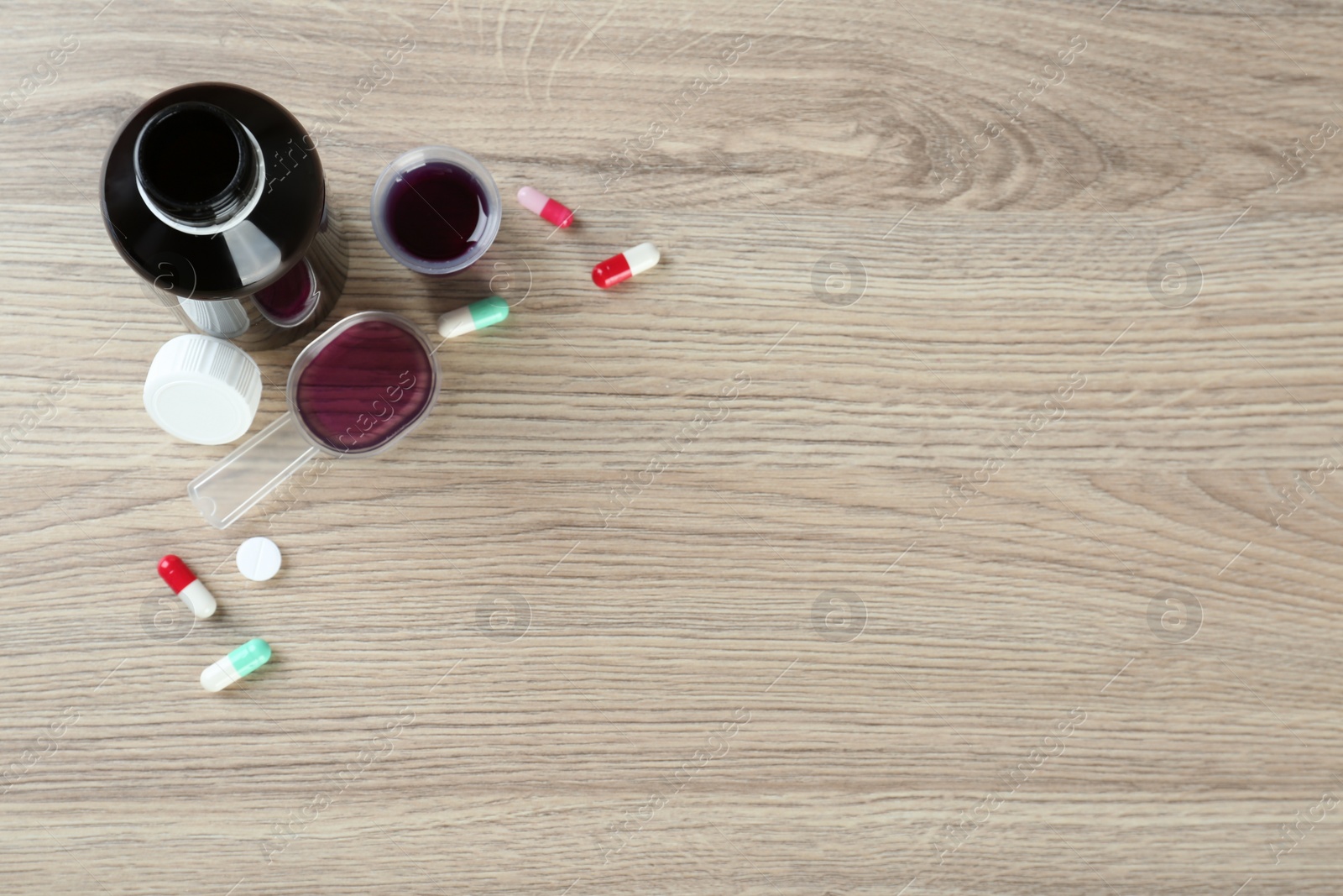Photo of Flat lay composition with cough syrup and pills on wooden background. Space for text