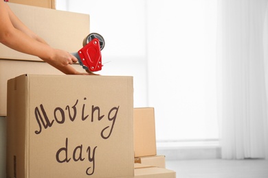 Photo of Woman packing carton box indoors, closeup. Moving day