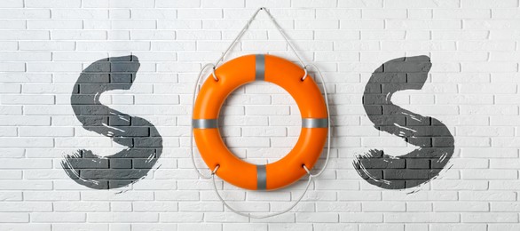 SOS message made from lifebuoy and letters on white brick wall. Banner design