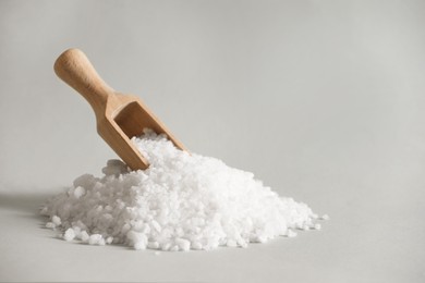 Photo of Organic salt and wooden scoop on light grey background. Space for text