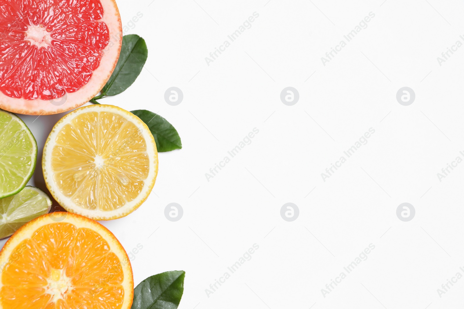 Different cut citrus fruits and leaves on white table, flat lay. Space for text Photo of Different cut citrus fruits and leaves on white table, flat lay. Space for text