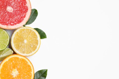 Photo of Different cut citrus fruits and leaves on white table, flat lay. Space for text