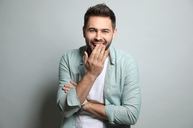 Young man laughing on light grey background. Funny joke