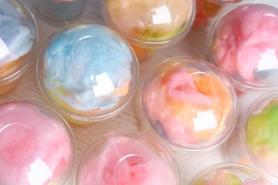 Photo of Many plastic cups with tasty cotton candies on white wooden table, above view