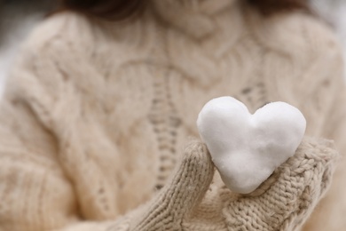 Photo of Woman holding heart made of snow, closeup view