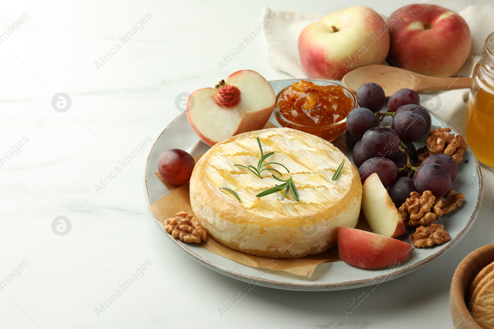 Photo of Tasty baked brie cheese served on white marble table. Space for text