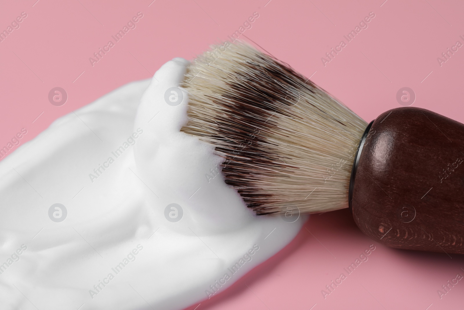 Photo of Brush with shaving foam on pink background, closeup