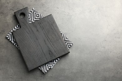 Black cutting board and napkin on grey table, top view. Space for text