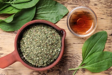 Flat lay composition with broadleaf plantain oil and dried leaves on wooden table