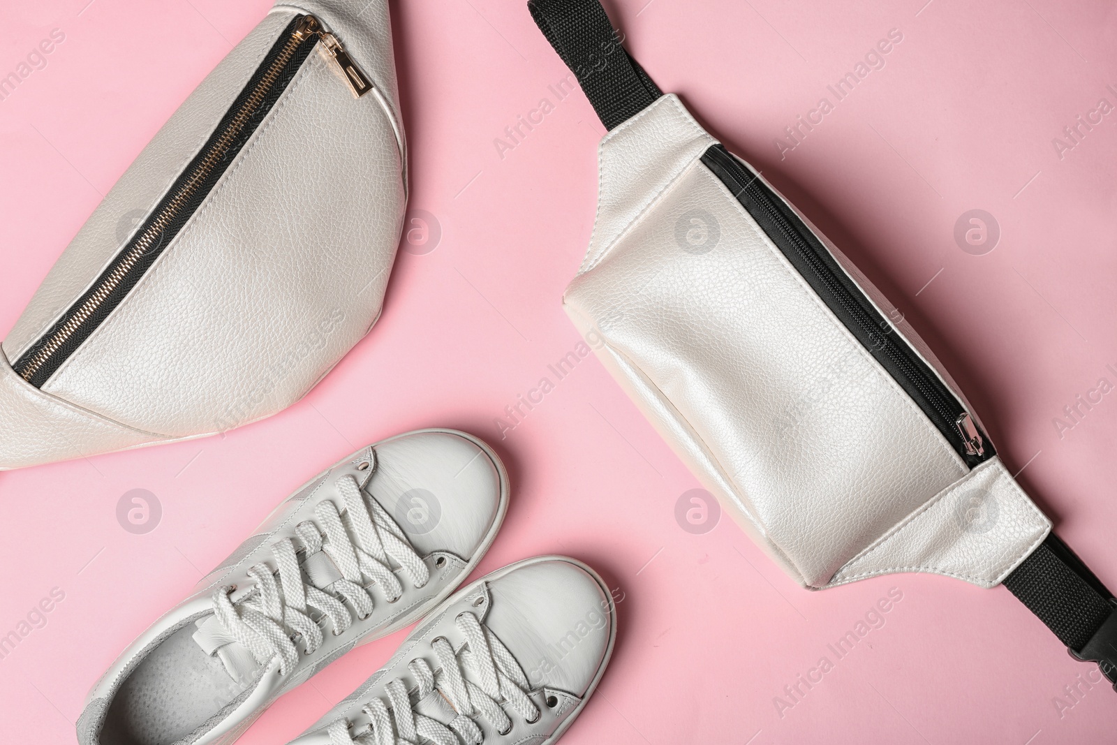 Photo of Flat lay composition of stylish shoes and bum bags on color background