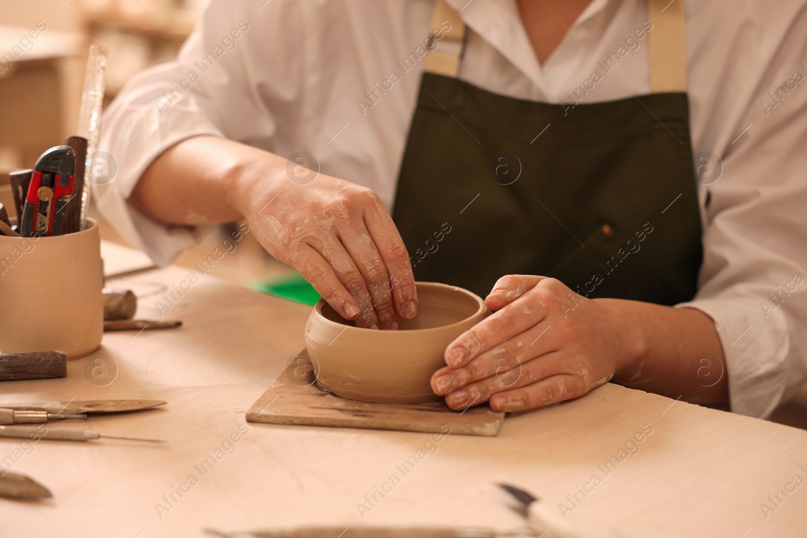 Photo of Pottery crafting. Woman sculpting with clay at table, closeup