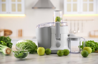 Photo of Modern juicer with fresh fruits on table in kitchen