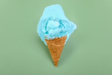 Photo of Melted ice cream and wafer cone on green background, top view