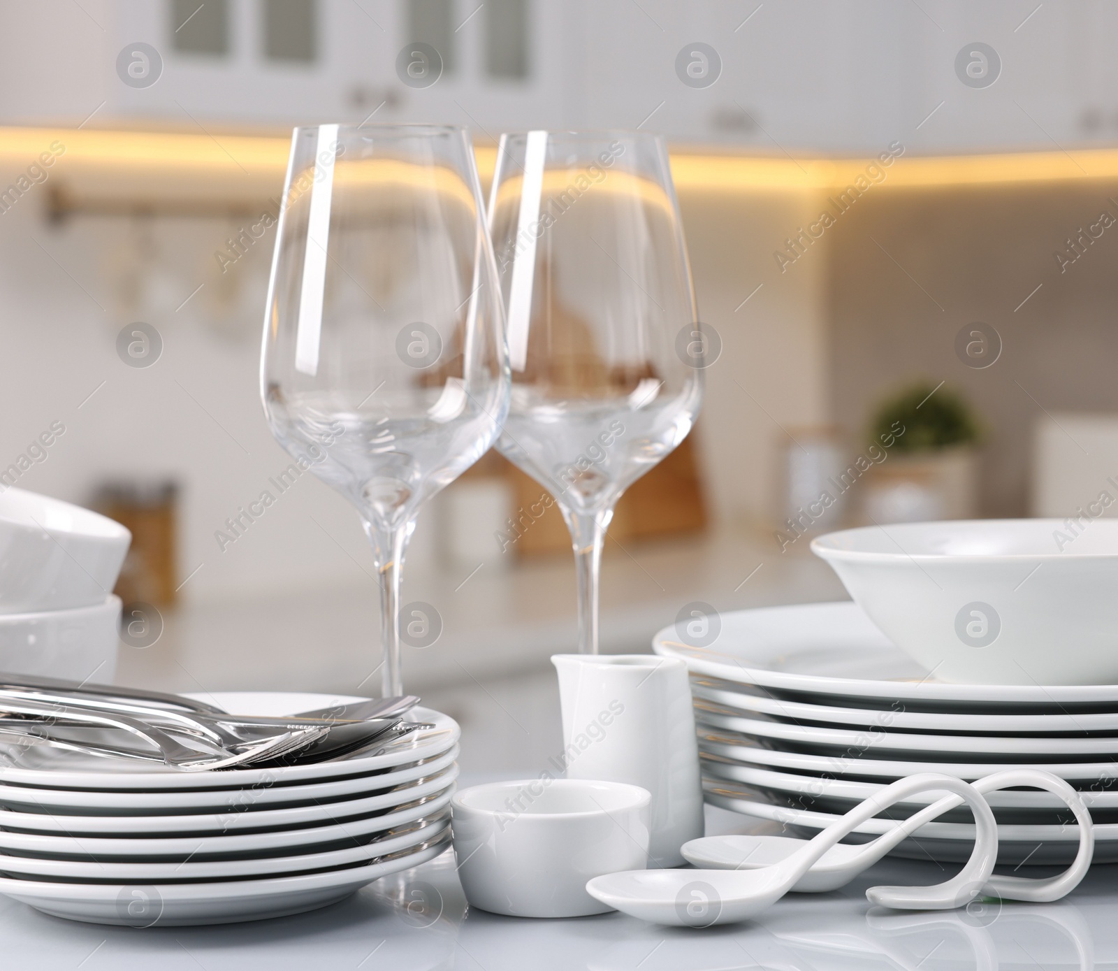 Photo of Set of clean dishware, glasses and cutlery on table in kitchen