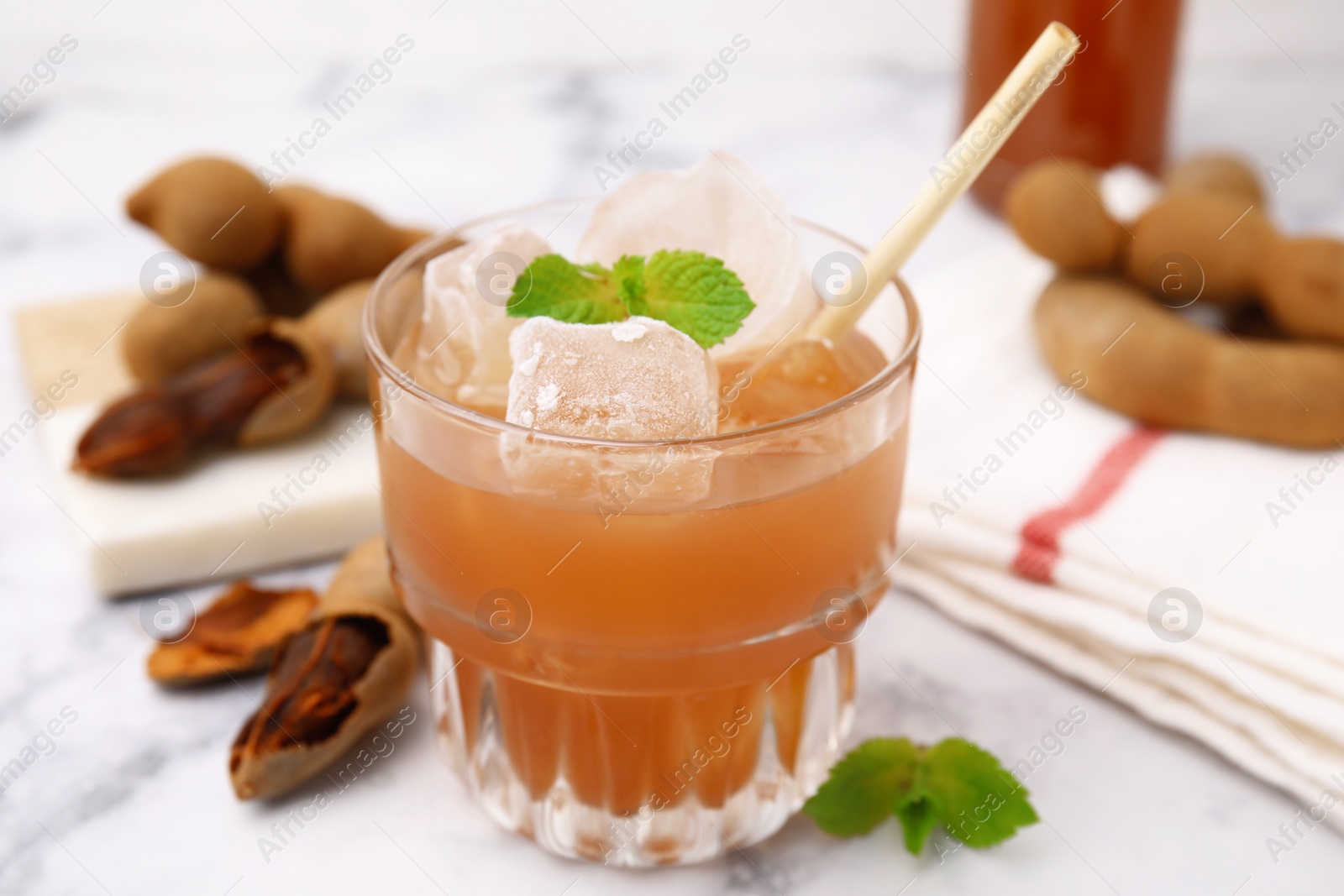 Photo of Freshly made tamarind juice with mint on white marble table, closeup