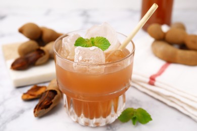 Photo of Freshly made tamarind juice with mint on white marble table, closeup