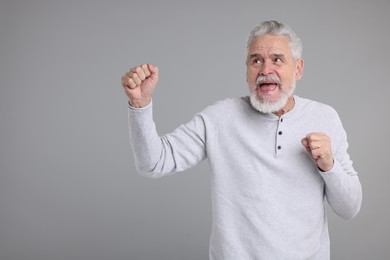 Photo of Portrait of surprised senior man on grey background, space for text