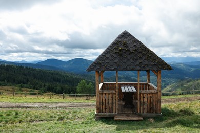 Picturesque view of wooden gazebo in mountains, space for text
