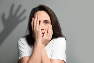 Image of Paranoid individual. Scared woman having delusion as hand reaching for her on grey background