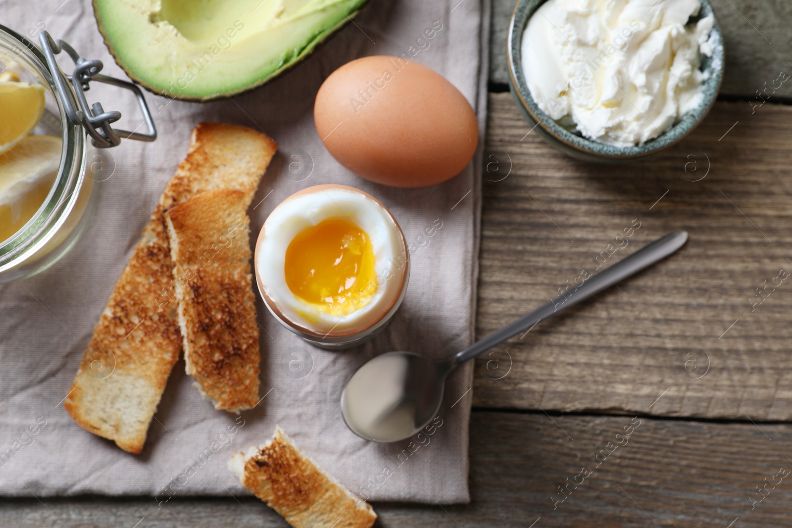 Photo of Soft boiled egg served for breakfast on wooden table, flat lay