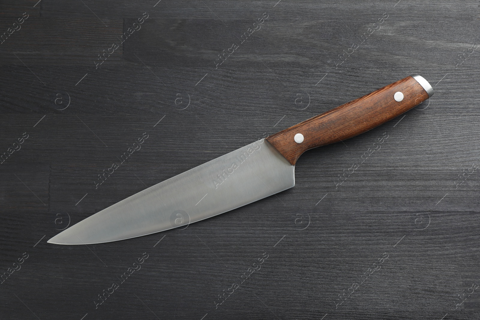 Photo of One sharp knife on black wooden table, top view