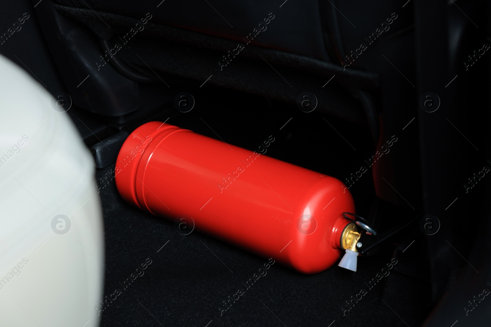 Photo of Red fire extinguisher in trunk. Car safety equipment