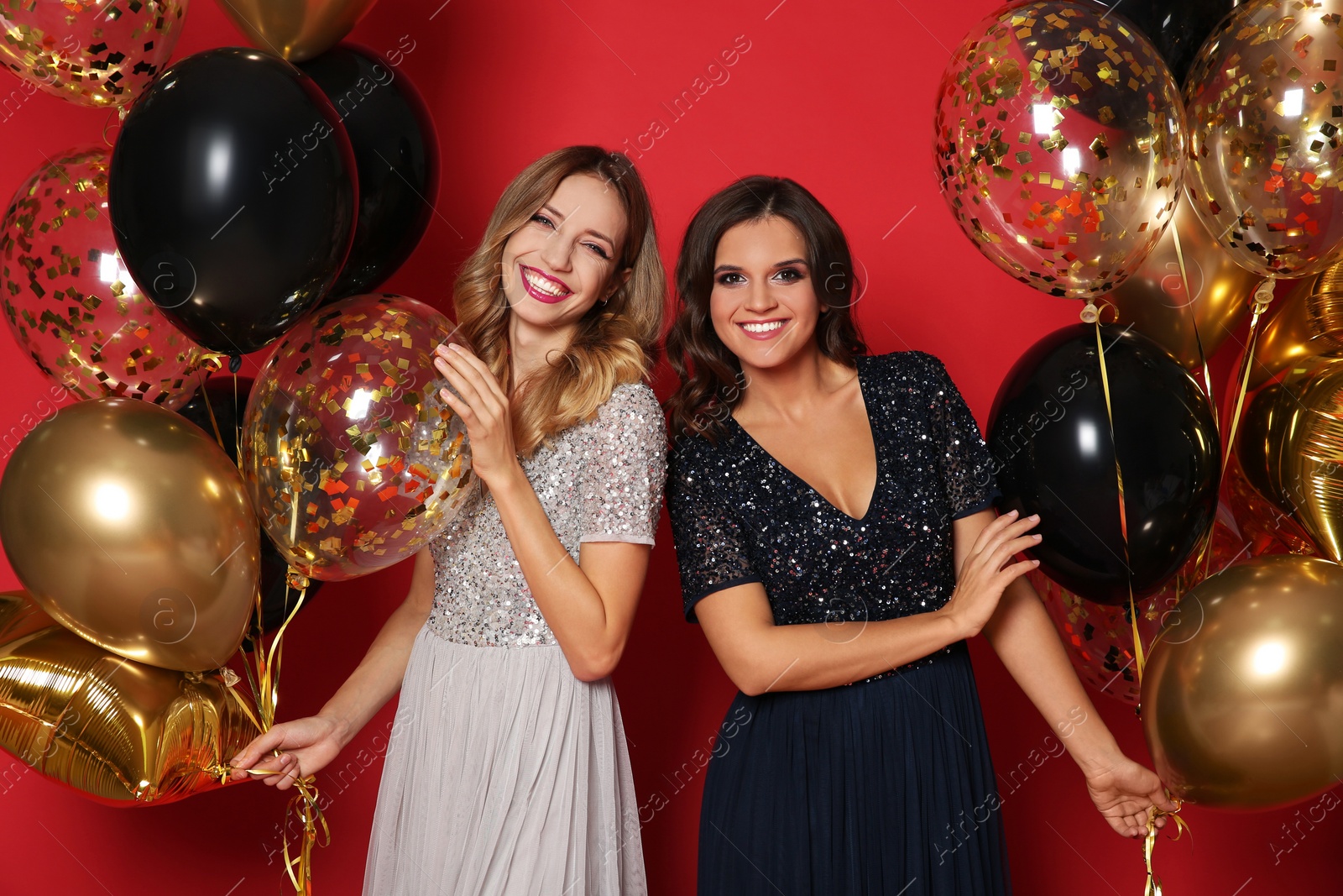 Photo of Happy women with air balloons on red background. Christmas party