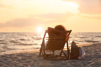 Photo of Woman resting in wooden sunbed on tropical beach at sunset