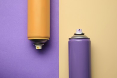 Photo of Cans of different spray paints on color background, flat lay. Graffiti supplies