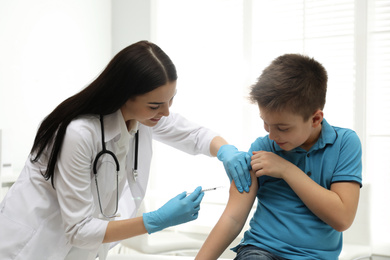 Photo of Doctor vaccinating little child in modern clinic