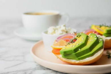 Plate of sandwiches with sliced salmon and avocado served on white marble table