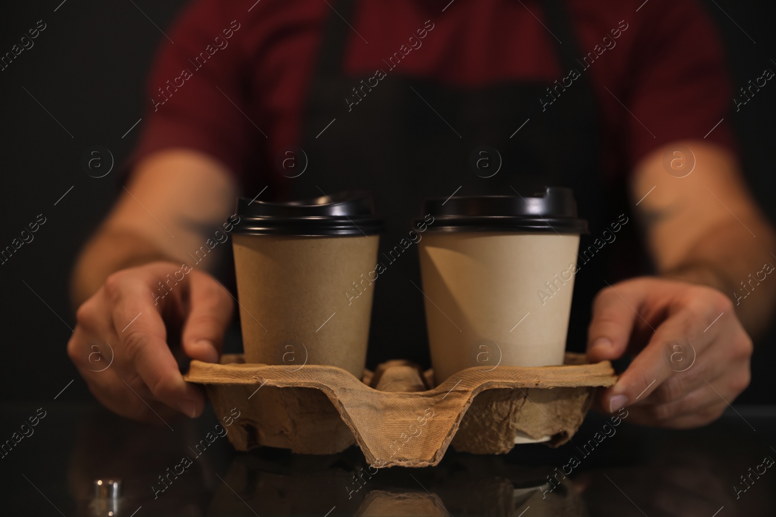 Photo of Barista putting takeaway coffee cups with cardboard holder on glass table, closeup