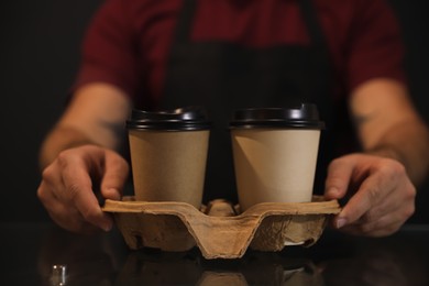 Photo of Barista putting takeaway coffee cups with cardboard holder on glass table, closeup