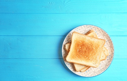 Photo of Plate with toasted bread on wooden background, top view