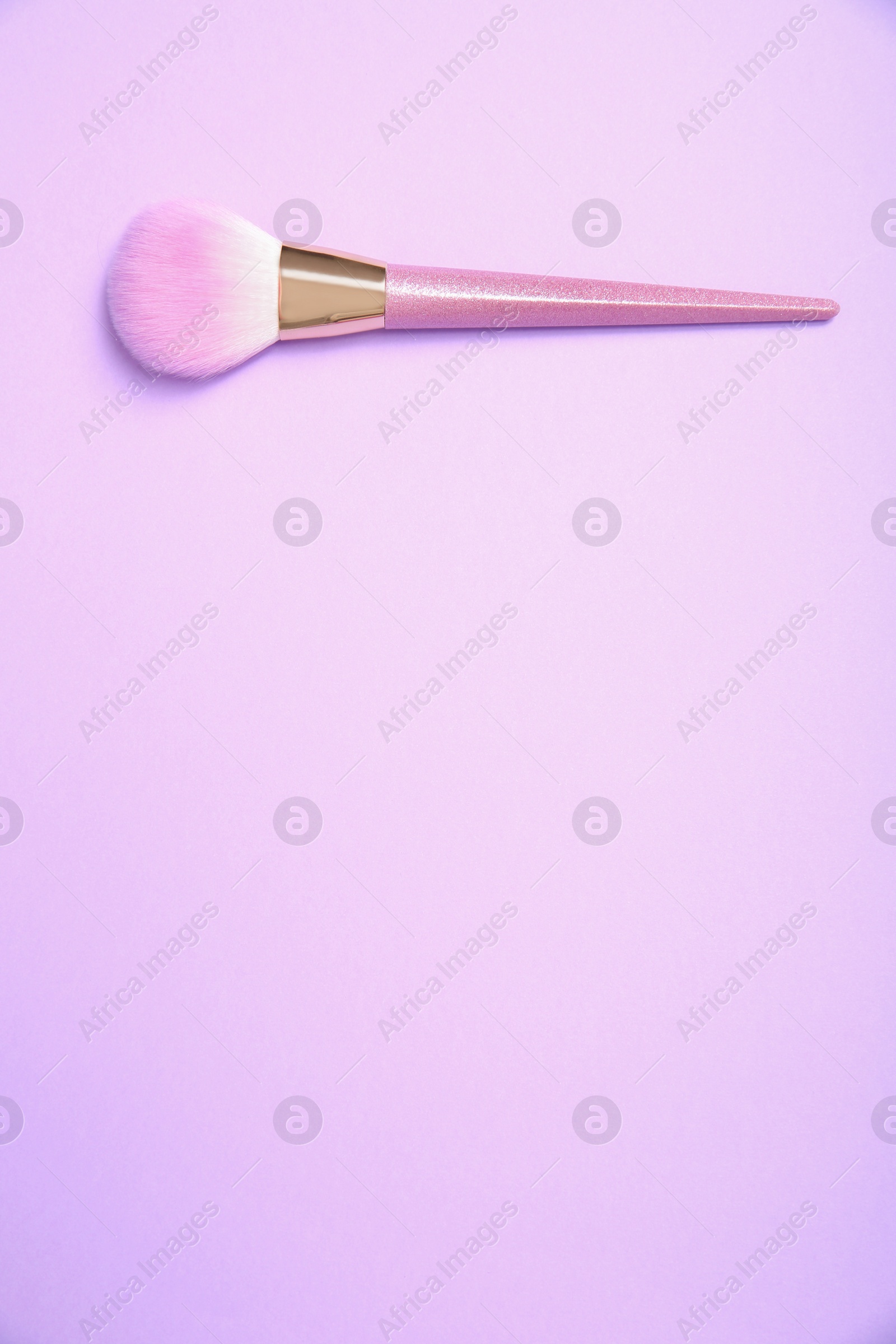 Photo of Professional makeup brush on lilac background, top view. Space for text