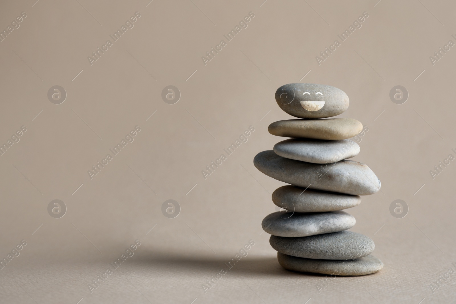 Image of Stack of stones with drawn happy face on beige background, space for text. Be in harmony and enjoying your life