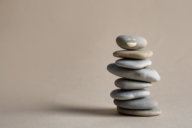 Image of Stack of stones with drawn happy face on beige background, space for text. Be in harmony and enjoying your life