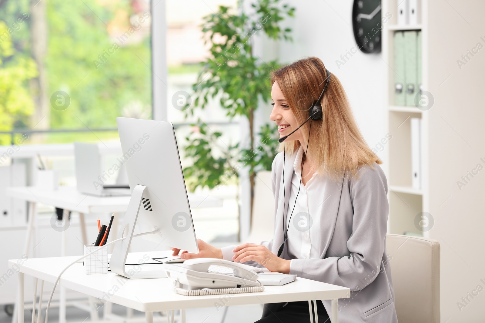 Photo of Female receptionist with headset at desk in office