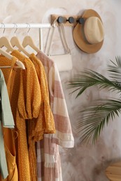 Different stylish clothes hanging on rack in room