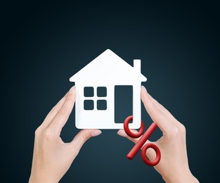 Mortgage concept. Woman holding house model on color background, closeup