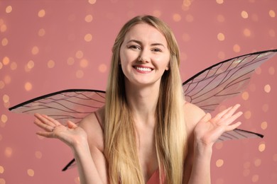 Photo of Beautiful girl in fairy costume with wings on pink background